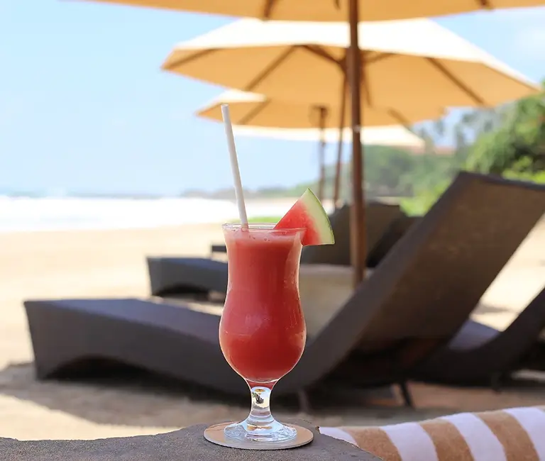View of the beach, sun beds are place and fres watermelon juice on the table